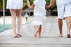 Rear View Of Family Walking On Wooden Jetty