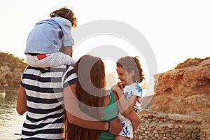 Rear View Of Family Watching Sunset Over Harbour