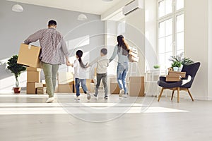 Rear view on father, mother and kids walking with boxes in new home room