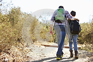 Rear View Of Father And Son Hiking In Countryside