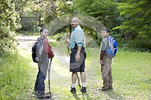 Rear view father and sons hiking in woods on trail