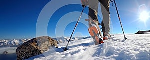 Rear view of the feet of a mountaineer walking on snow with poles in a high mountain landscape. Adventure sports concept