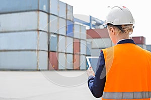 Rear view of female engineer using digital tablet in shipping yard