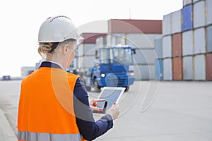 Rear view of female engineer using tablet PC in shipping yard