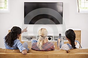 Rear View Of Female Friends Sitting On Sofa Watching Television