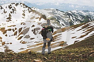 Rear view of female hiker with backpack standing on top of the mountain