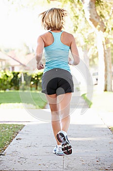 Rear View Of Female Runner Exercising On Suburban Street