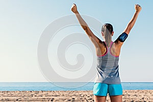 Rear view of female runner raising arms.
