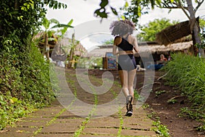 Rear view female runner training on countryside road - young attractive and fit jogger woman doing running workout outdoors at