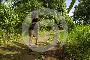 Rear view female runner training on countryside road - young attractive and fit jogger woman doing running workout outdoors at