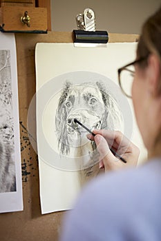 Rear View Of Female Teenage Artist Sitting At Easel Drawing Picture Of Dog In Charcoal