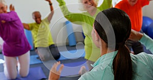 Rear view of female trainer training senior people in exercise at fitness studio 4k