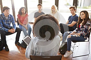 Rear View Of Female Tutor Leading Discussion Group Amongst High School Pupils