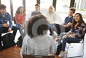 Rear View Of Female Tutor Leading Discussion Group Amongst High School Pupils