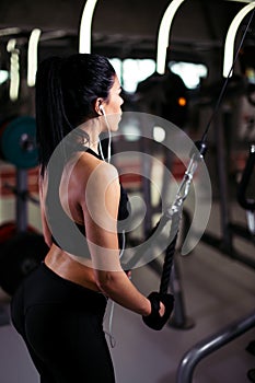 Rear view fit woman execute exercise with exercise-machine Cable Crossover in gym