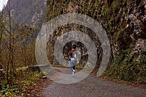 Rear view on fit woman exercise by running on the road near forest mountains, side view