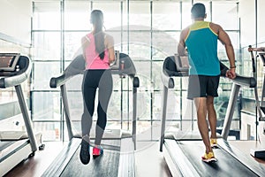 Rear view of a fit woman and her cardio workout partner running