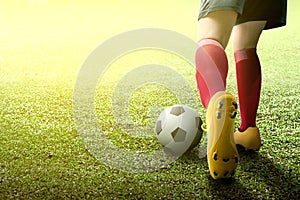 Rear view of football player woman in orange jersey kicking the ball