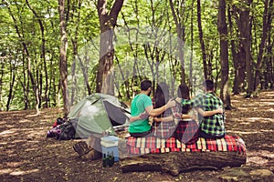 Rear view of four serene tourists friends sitting and bonding on