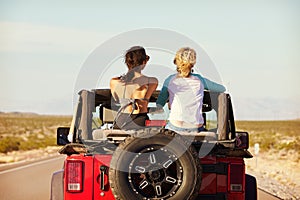 Rear View Of Friends On Road Trip Driving In Convertible Car