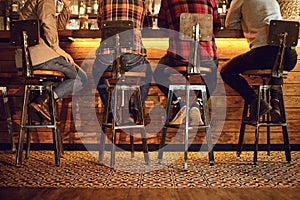 Rear view friends sitting on chairs talking at the bar in a bar.