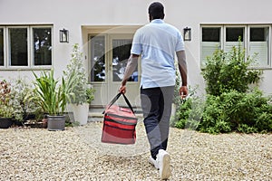 Rear View Of Gig Economy Driver Delivering Online Takeaway Food Order To House