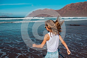 Rear view of girl on beach. Blonde girl enjoying sandy beach, looking at crystalline sea in Canary Islands. Concept of