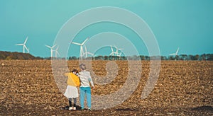 Rear view of girl and boy in front of the wind turbines farm. concept of sustainable resources and renewable energy