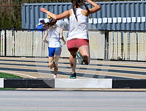 Rear view of girl jumping into the steeplechase water jump during a race