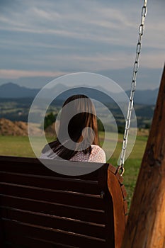 Rear view of a girl sittig on a swing enjoying the view, vertical