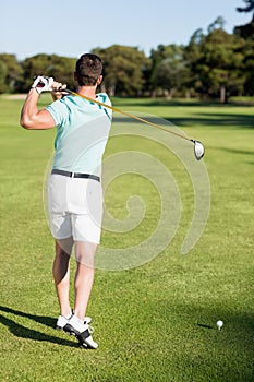 Rear view of golfer man taking shot