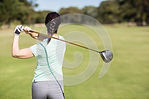 Rear view of golfer woman taking shot