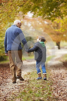 Rear View Of Grandfather And Grandson Walking Along Path