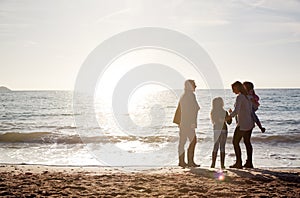 Rear View Of Grandmother With Mother And Granddaughters Standing Silhouetted By Sea