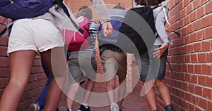 Rear view of group of kids with backpacks running