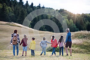 Rear view of group of school children with teacher on field trip in nature.