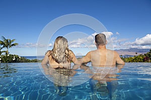 Rear view of handsome couple in an infinity pool looking out tropical island landscape in Hawaii