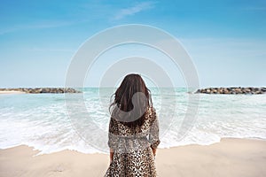 Rear view happiness traveller young asian woman in beautiful dress standing on sandy beach. Cute girl enjoy her tropical sea on
