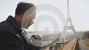 Rear view happy freelance photographer man taking a picture of Eiffel Tower in Paris with retro film camera slow motion.