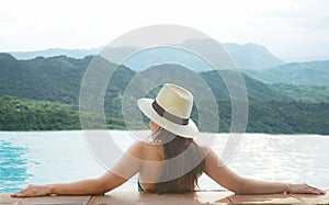 Rear view of happy lifestyle women relax and enjoy in the pool looking at mountain landscape. Women together on summer and vacati