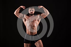 Rear view of healthy muscular young man with his arms stretched out isolated on black background