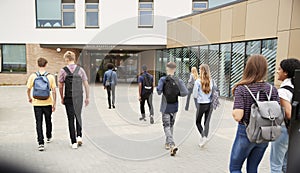 Rear View Of High School Students Walking Into College Building Together photo