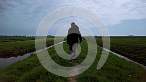 Rear View Hiking Boy Alone in rural landscape on cloudy day in the Netherlands