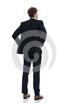Rear view hopeful businessman holding his hands on his waist