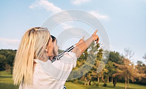 Rear view hotizontal image of cute daughter with her smiling mother point up to the sky. Loving woman and her little girl playing