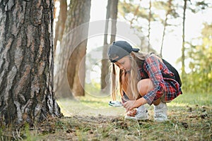 Rear view image of cute little girl exploring the nature with magnifying glass outdoor. Child playing in the forest with