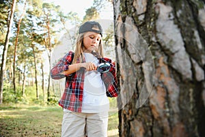 Rear view image of cute little girl exploring the nature with magnifying glass outdoor. Child playing in the forest with