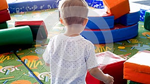 Rear view image of little toddler boy playing on playground with soft objects