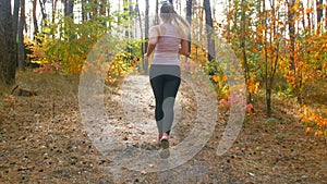 Rear view image of young fit woman running at autumn forest