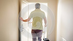 Rear view image of young tourist man walking in hotel room